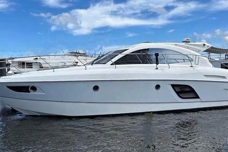 The Image of 2014 Beneteau Gran Turismo 49 yacht docked in a marina under a cloudy sky. - 0