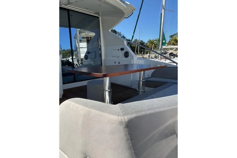 Slide: The Image of 2014 Beneteau Gran Turismo 49 yacht with outdoor seating and table, docked under clear skies. - 6