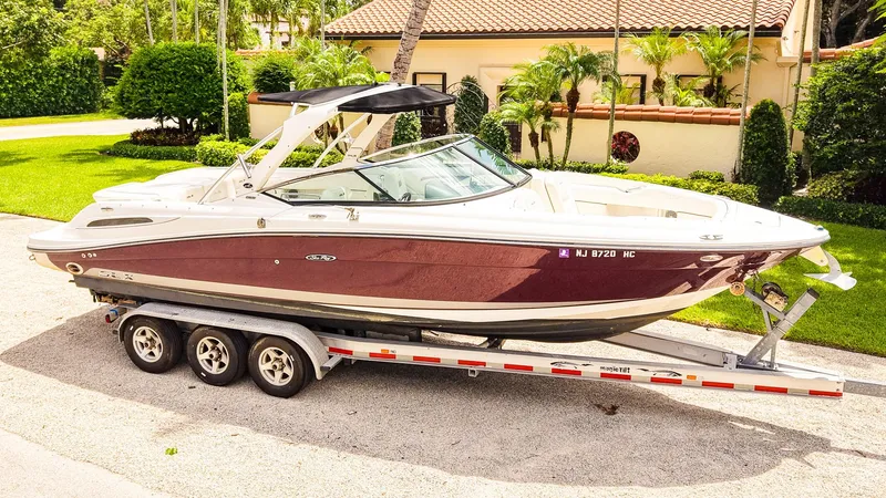 The Image of 2010 Sea Ray 270 SLX boat on trailer, parked in a sunny residential area. - 1