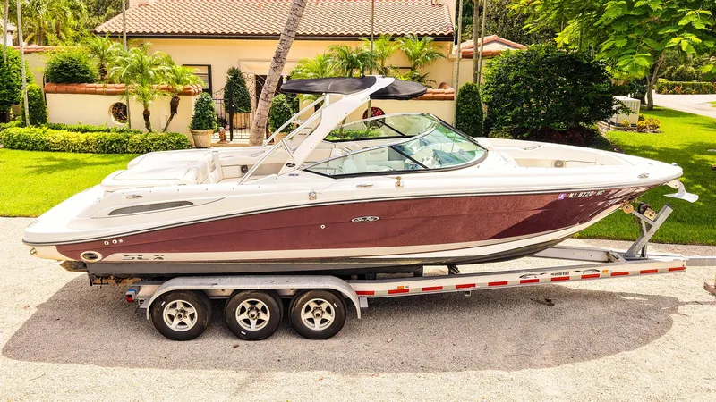 Slide: The Image of 2010 Sea Ray 270 SLX boat on trailer, parked in a sunny residential area. - 2