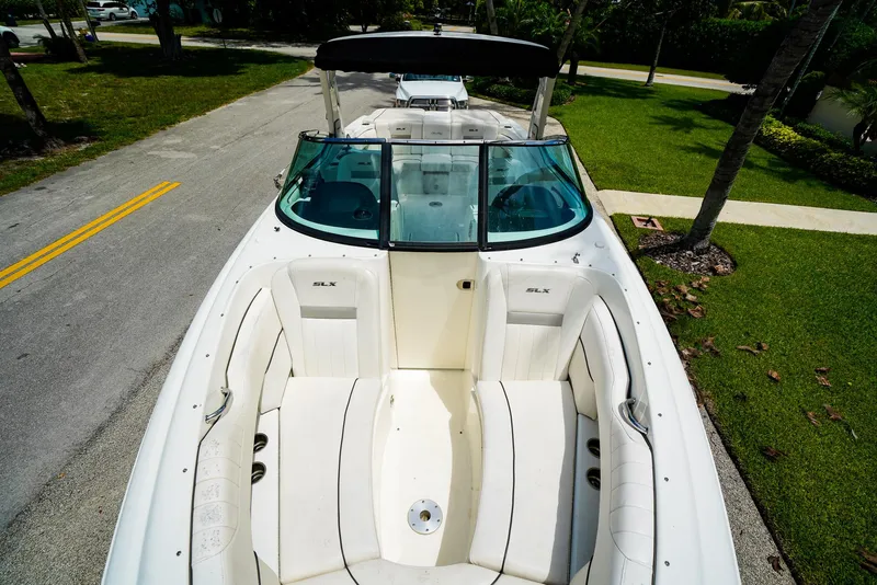 Slide: The Image of 2010 Sea Ray 270 SLX boat with white seating, parked on a residential street. - 26