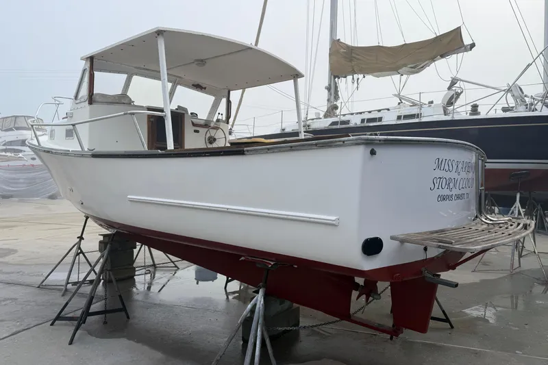 Slide: The Image of 1983 SISU 26 boat on stands, white hull, docked in a marina. - 10