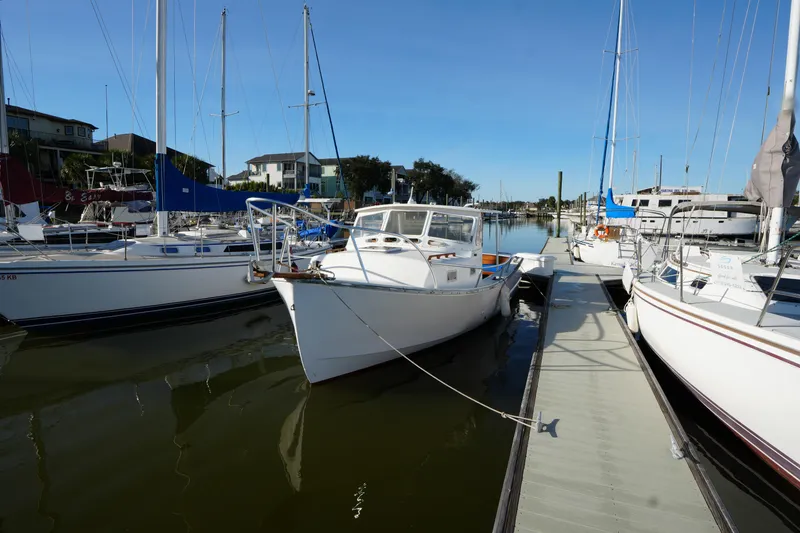 Slide: The Image of 1983 SISU 26 boat docked among sailboats in a marina under clear blue skies. - 3