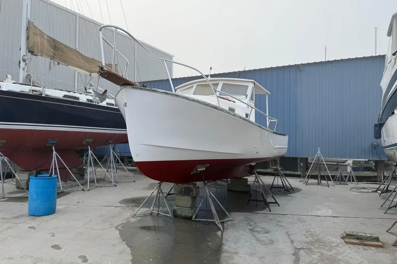 Slide: The Image of 1983 SISU 26 boat on stands in a shipyard, blue and white hull. - 7