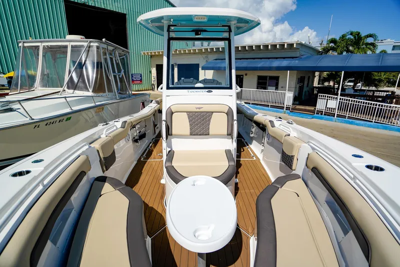Slide: The Image of 2021 Tidewater 256 LXF boat with spacious seating and modern design at a marina. - 24