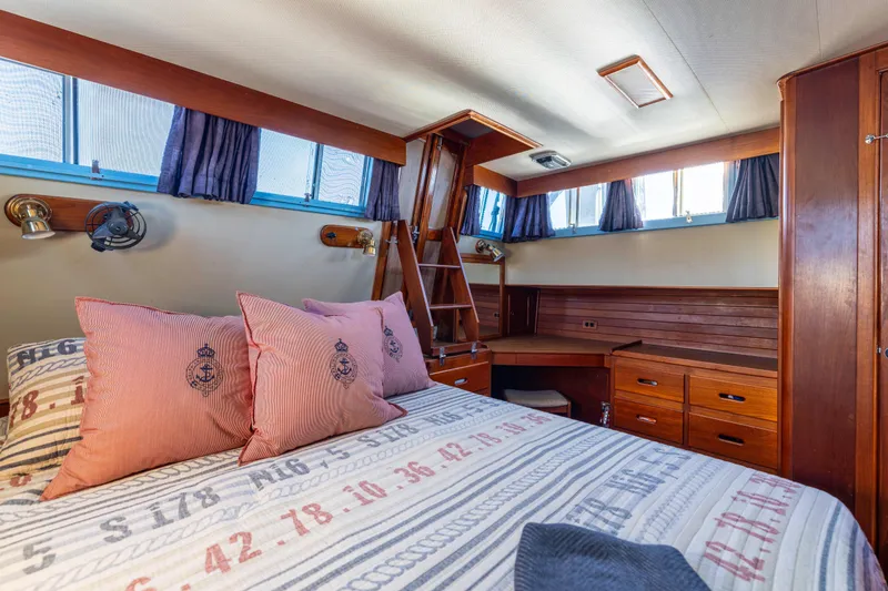 Slide: The Image of 1989 Grand Banks 46 Classic yacht cabin with wooden interior and nautical-themed bedding. - 29