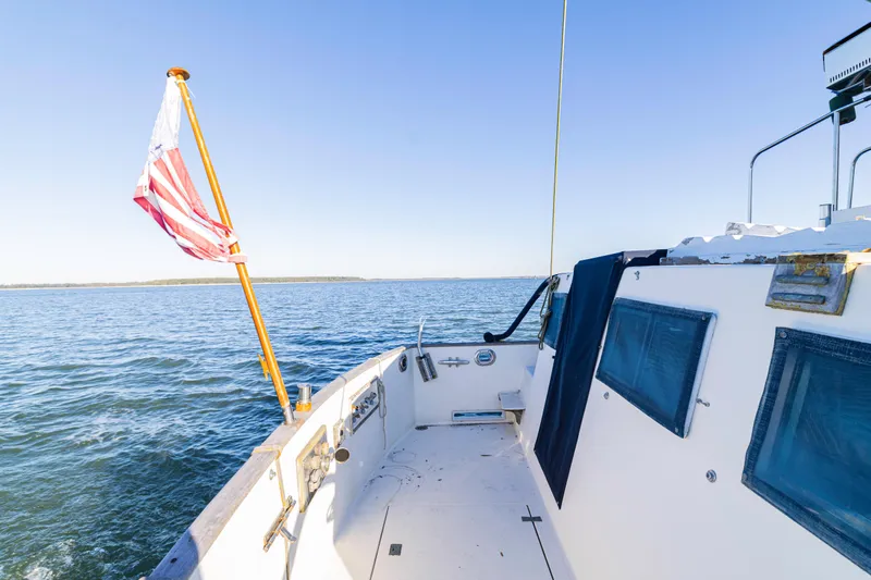 Slide: The Image of 1989 Grand Banks 46 Classic yacht deck with American flag, cruising on open water. - 51