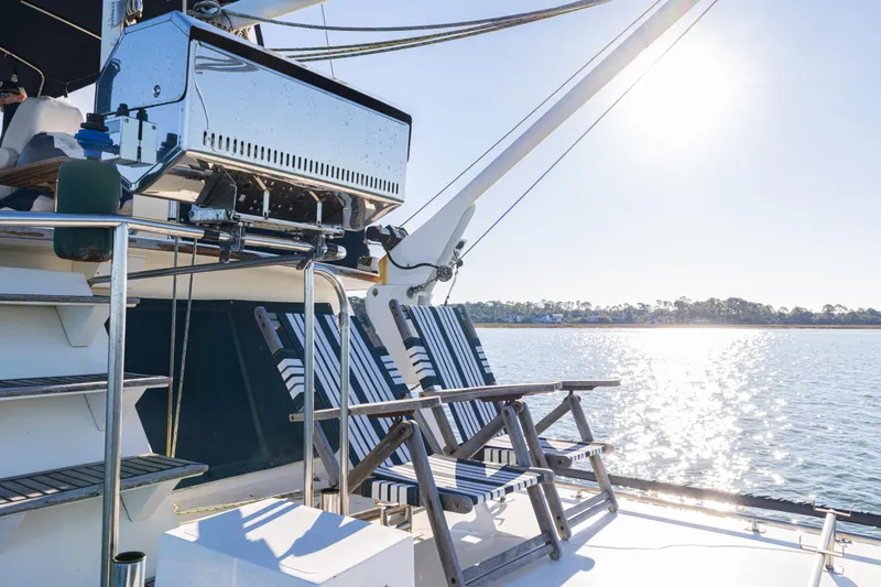 Slide: The Image of 1989 Grand Banks 46 Classic yacht deck with striped chairs and sunny waterfront view. - 53