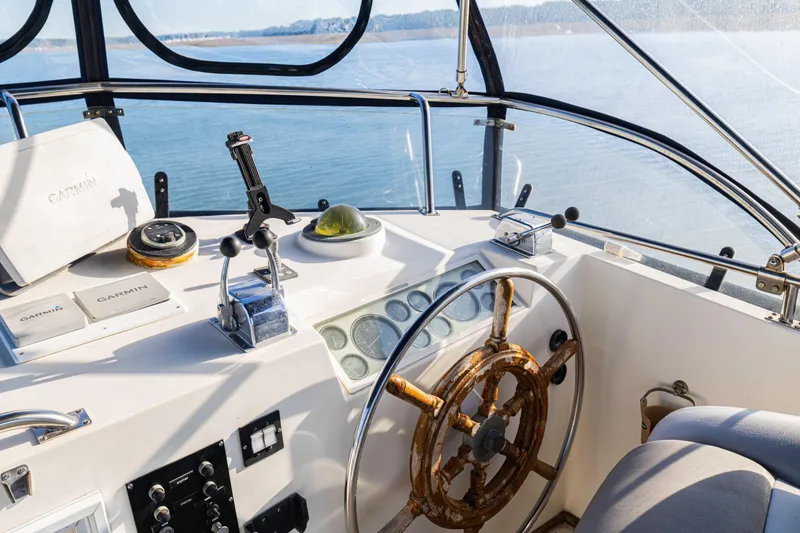 Slide: The Image of Helm of 1989 Grand Banks 46 Classic yacht with navigation equipment and wooden wheel. - 58