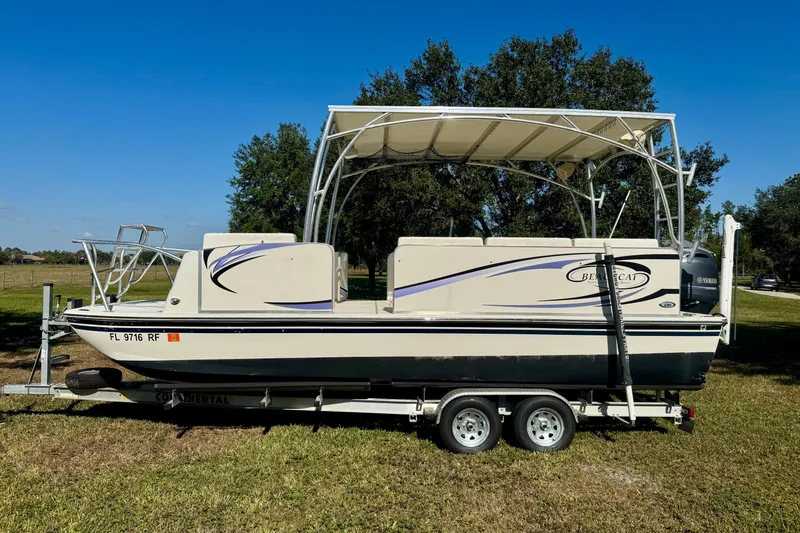 Slide: The Image of 2017 Beachcat 230 boat on trailer with canopy, parked on grass. - 0