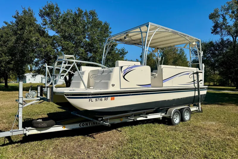 Slide: The Image of 2017 Beachcat 230 boat on trailer, parked on grass under clear blue sky. - 1