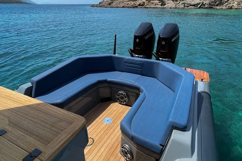 Slide: The Image of 2026 Rock Marine RM 36 boat with blue seating, dual engines, and wooden deck on clear water. - 11