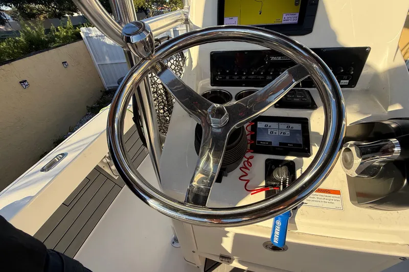 Slide: The Image of Steering wheel and dashboard of 2022 Pathfinder 2005 TRS boat, featuring navigation controls. - 57