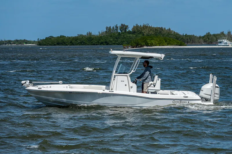 Slide: The Image of 2021 Caymas 26 HB boat cruising on a sunny day with lush greenery in the background. - 15