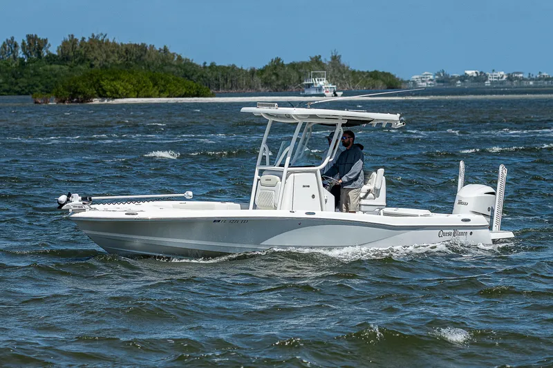 Slide: The Image of 2021 Caymas 26 HB boat cruising on a sunny day, with lush greenery in the background. - 16
