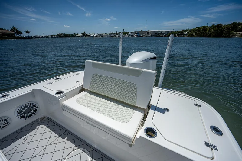 Slide: The Image of 2021 Caymas 26 HB boat with cushioned seating, on a calm waterway under a clear sky. - 19
