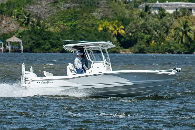 Slide: The Image of 2021 Caymas 26 HB boat cruising on a scenic waterway with lush greenery. - 2