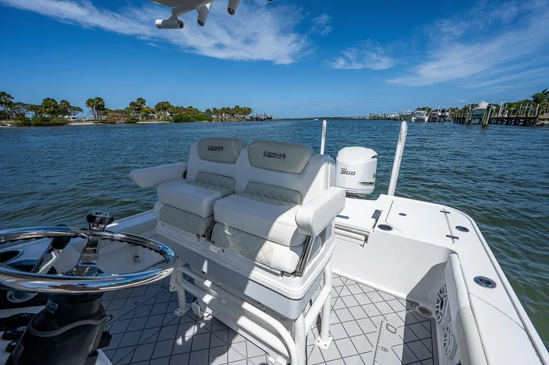 Slide: The Image of 2021 Caymas 26 HB boat with white seating, steering wheel, and scenic water view. - 21