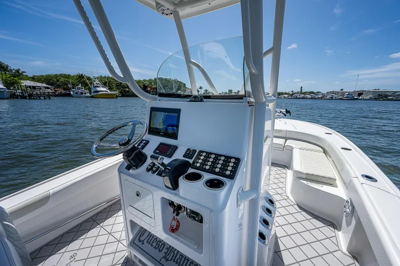 Slide: The Image of 2021 Caymas 26 HB boat interior with helm, steering wheel, and navigation system on a sunny day. - 24