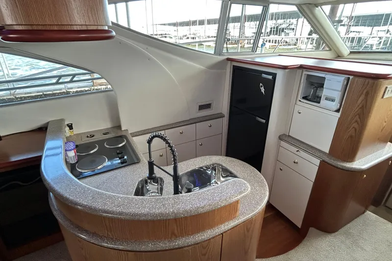 Slide: The Image of 1999 Maxum 4600 SCB yacht interior with white seating and table, overlooking water. - 29