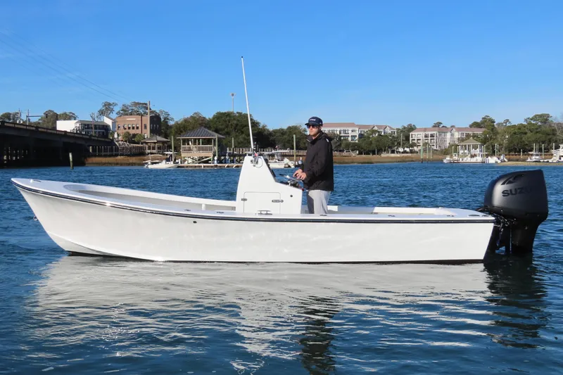 Slide: The Image of 1982 Privateer 20 Roamer Skiff on water, man steering, clear day, waterfront background. - 11