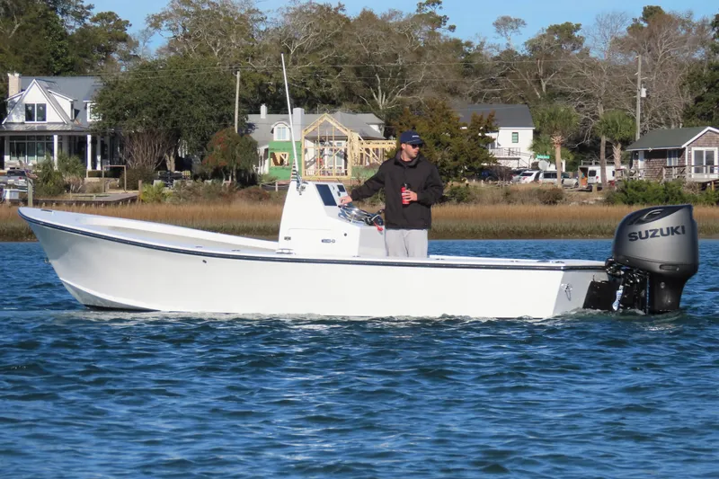 Slide: The Image of 1982 Privateer 20 Roamer Skiff with Suzuki outboard on calm water near shoreline homes. - 13