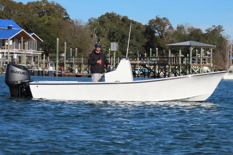 Slide: The Image of 1982 Privateer 20 Roamer Skiff on water, with Suzuki outboard motor, near docks. - 14