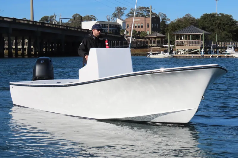Slide: The Image of 1982 Privateer 20 Roamer Skiff on water, with person steering near a bridge. - 3