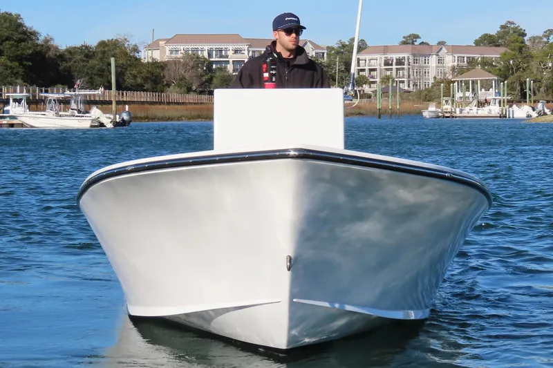 Slide: The Image of 1982 Privateer 20 Roamer Skiff on water, with person steering, coastal background. - 5