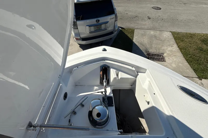 Slide: The Image of 2019 Blackfin 242 CC boat anchor compartment, open lid, parked near a Lexus SUV. - 18