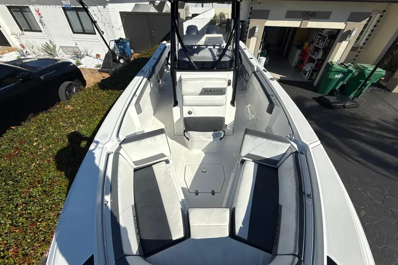 Slide: The Image of 2019 Blackfin 242 CC boat with spacious seating, parked in a residential driveway. - 19