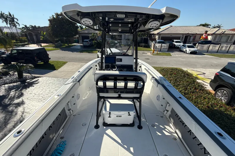 Slide: The Image of 2019 Blackfin 242 CC boat with T-top and console, parked in a residential driveway. - 7