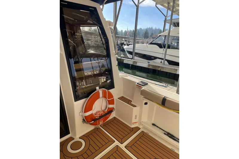 Slide: The Image of 2019 Ranger Tugs R-27 boat interior with life preserver and docked view. - 11