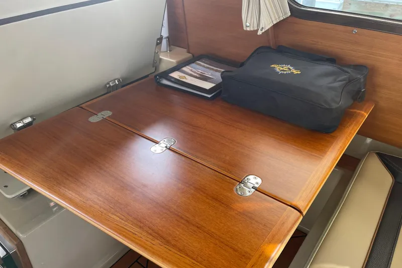Slide: The Image of 2019 Ranger Tugs R-27 interior with wooden table and storage bag. - 25