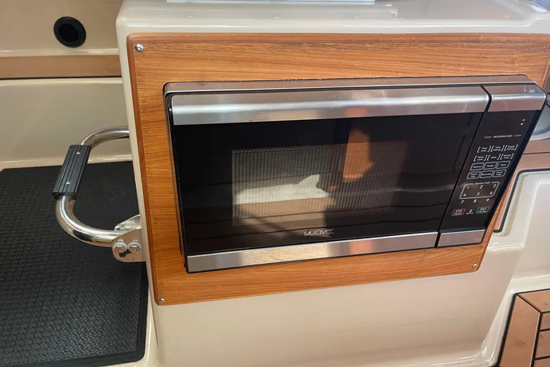 Slide: The Image of Microwave in 2019 Ranger Tugs R-27 boat interior, featuring wood paneling and stainless steel accents. - 28
