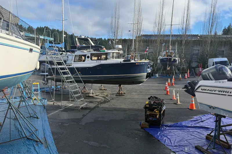 Slide: The Image of 2019 Ranger Tugs R-27 boat in a marina, surrounded by other vessels and maintenance equipment. - 42