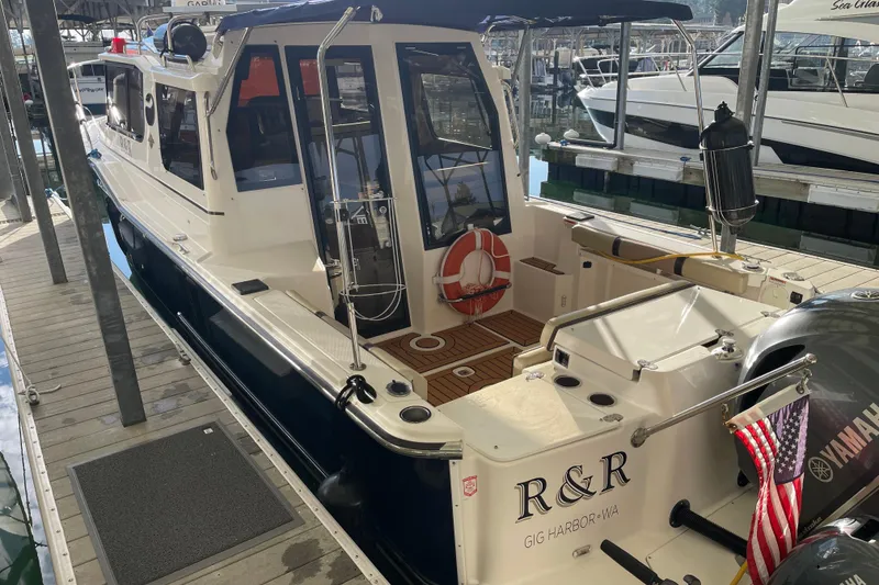 Slide: The Image of 2019 Ranger Tugs R-27 boat docked, featuring spacious deck and Yamaha engine. - 7