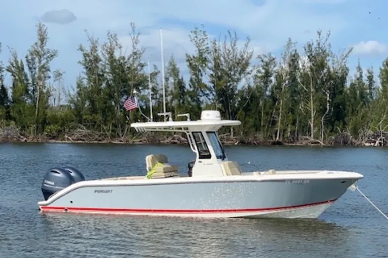 Slide: The Image of 2021 Pursuit S 268 Sport boat on calm water with trees in background. - 11