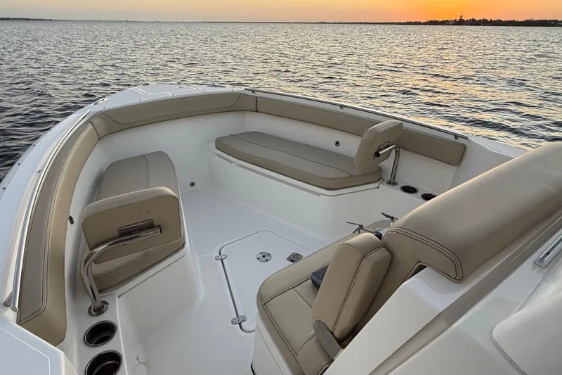 Slide: The Image of 2021 Pursuit S 268 Sport boat interior with beige seating at sunset on the water. - 16