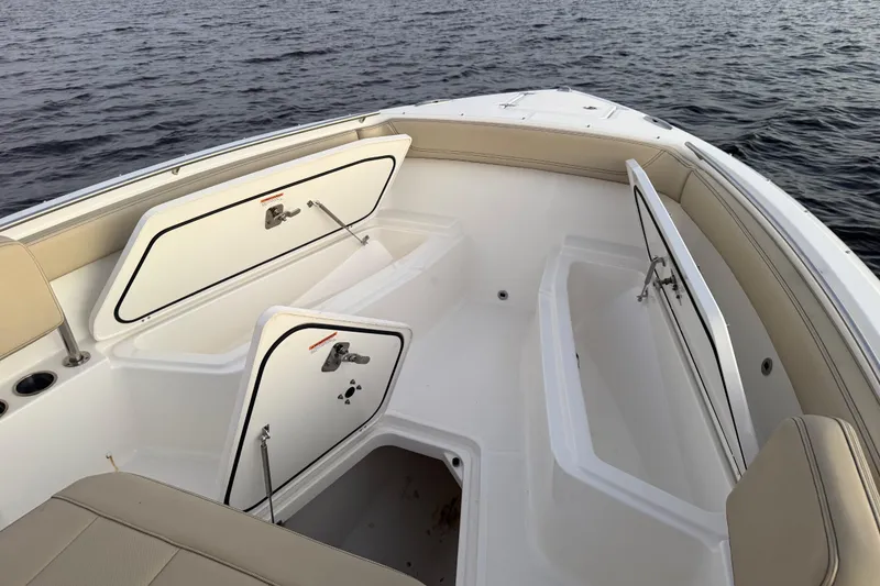 Slide: The Image of 2021 Pursuit S 268 Sport boat interior with open storage compartments on calm water. - 23