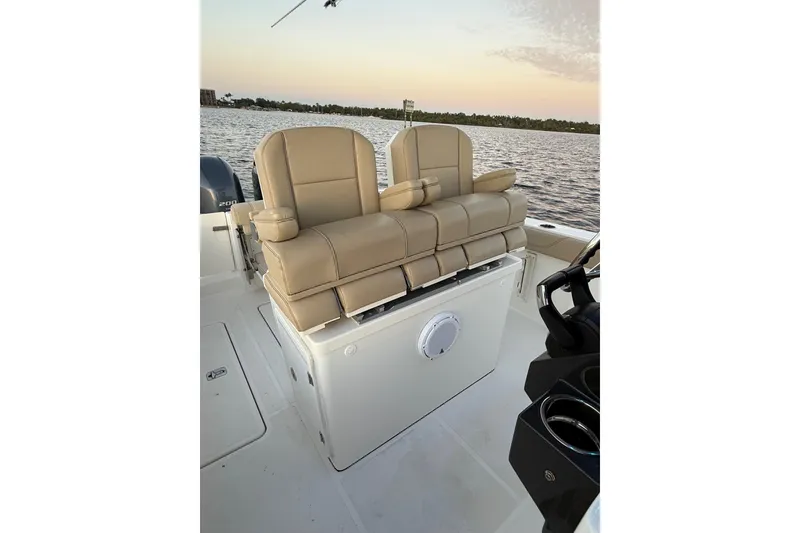 Slide: The Image of 2021 Pursuit S 268 Sport boat with beige seating, on calm water at sunset. - 25