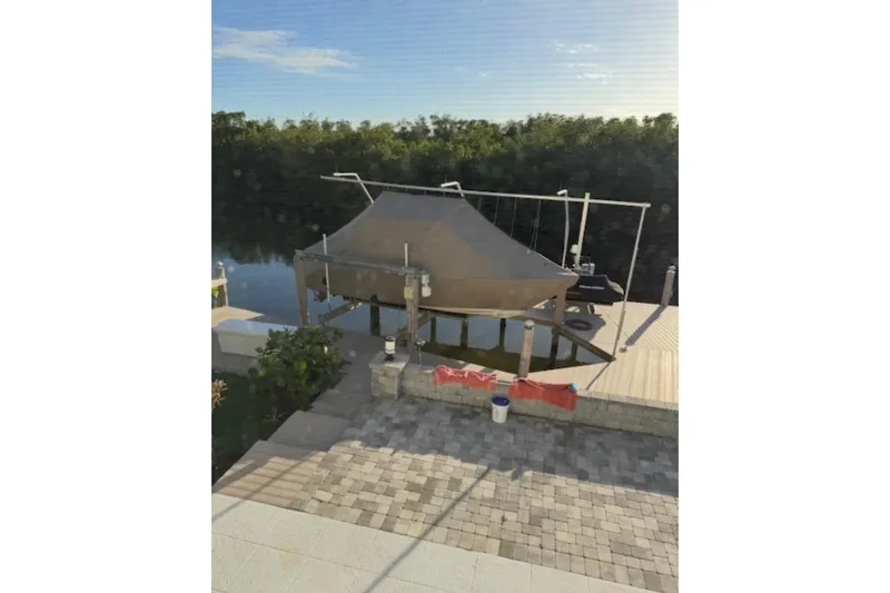 Slide: The Image of Docked 2021 Pursuit S 268 Sport boat under canopy by a serene waterfront. - 34