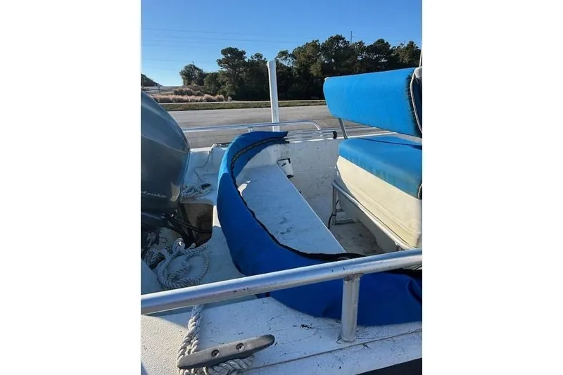 Slide: The Image of 2004 Carolina Skiff 17DLX boat interior with blue seating and motor, parked outdoors. - 11