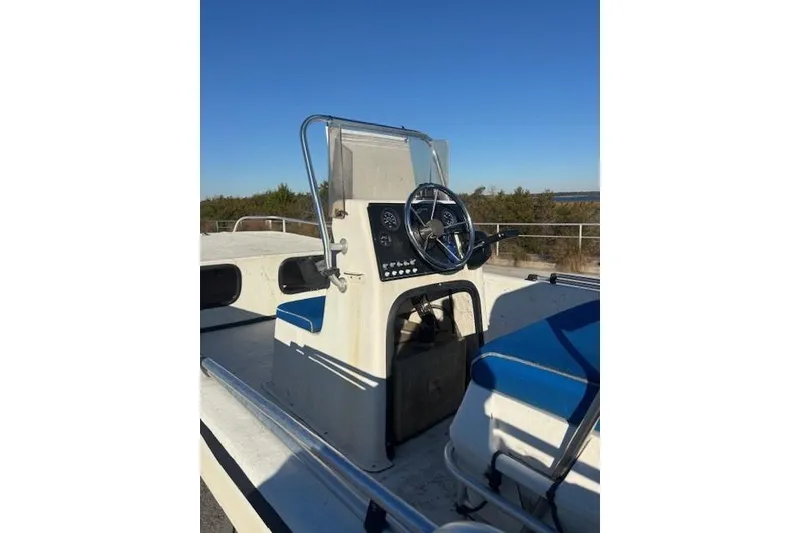 Slide: The Image of 2004 Carolina Skiff 17DLX boat console with steering wheel and blue seating. - 12
