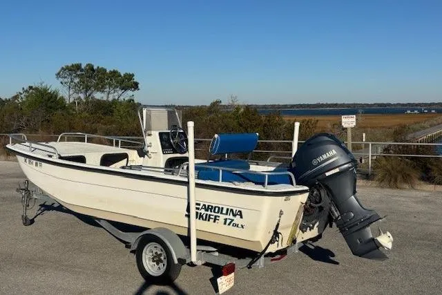 Slide: The Image of 2004 Carolina Skiff 17DLX boat on trailer with Yamaha outboard motor, parked near water. - 3