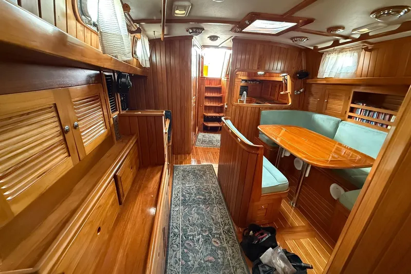 Slide: The Image of Luxurious interior of a 2000 Cabo Rico Cutter 45 sailboat with wood paneling and cozy seating. - 49