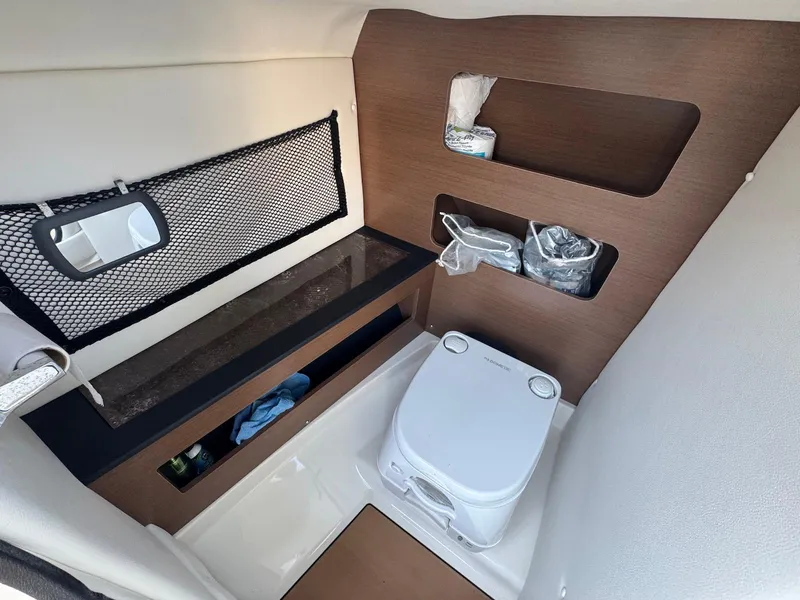 Slide: The Image of Interior of 2017 Sea Ray SDX 240 boat with compact toilet and storage shelves. - 3