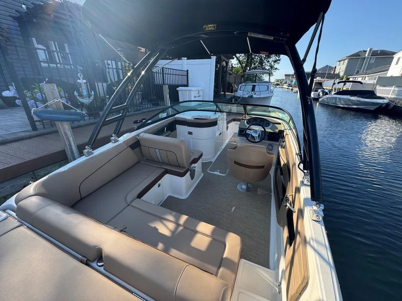 Slide: The Image of 2017 Sea Ray SDX 240 boat interior with seating and steering, docked in a canal. - 6