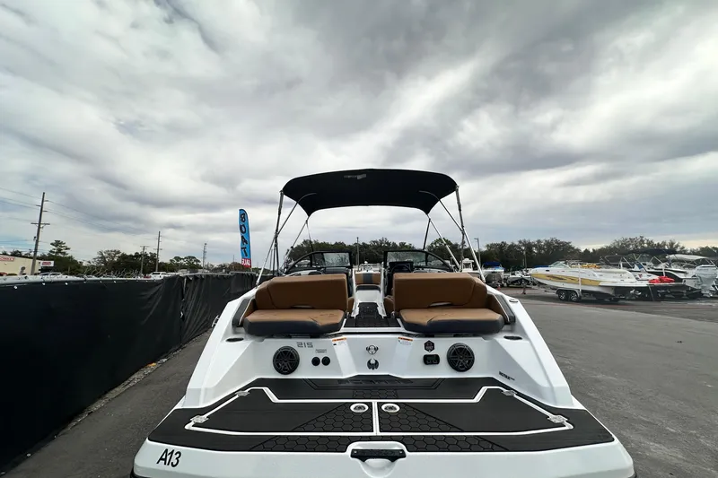 Slide: The Image of 2023 Scarab 215 ID boat with canopy, parked outdoors under cloudy sky. - 10