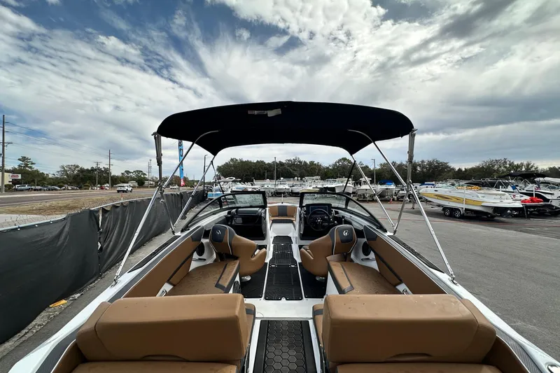Slide: The Image of 2023 Scarab 215 ID boat with canopy, parked outdoors under a cloudy sky. - 14